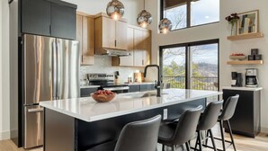 Una cocina moderna con un refrigerador de acero inoxidable, una isla grande con un lavamanos y una cafetera.