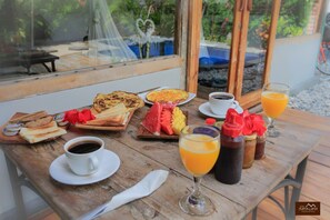 A breakfast table with toast, pancakes, fruit, coffee, and juice. - Villa Samalama Gili Air (Pemenang)