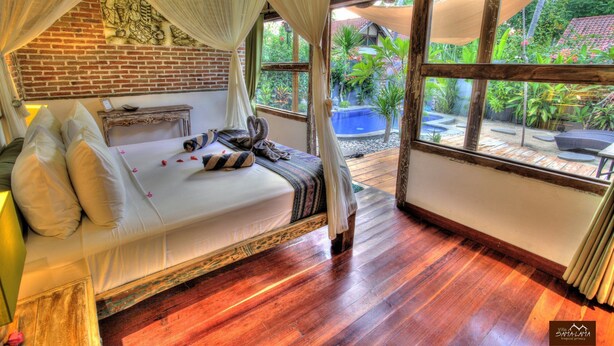 A room with a bed, a wooden floor, and a view of a pool and garden. - Villa Samalama Gili Air (Pemenang)