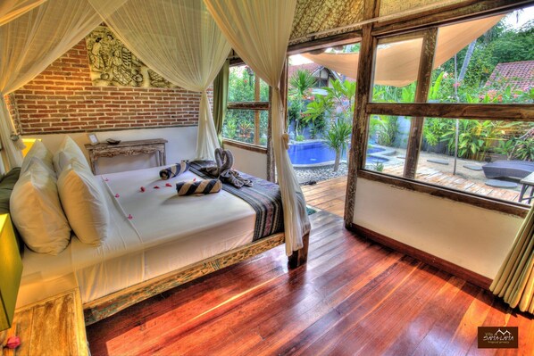Ein Zimmer mit Bett, Holzboden und Blick auf Pool und Garten.