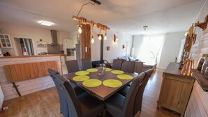 Un coin repas avec une table en bois, des chaises foncées et un luminaire suspendu moderne.