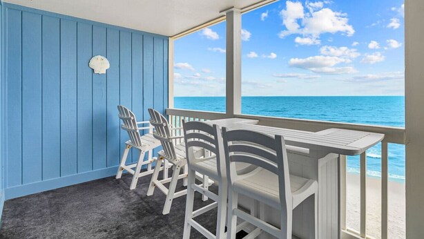 Une pièce avec vue sur l’océan, un mur bleu et une table avec des chaises.