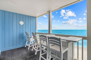 Une pièce avec vue sur l’océan, un mur bleu et une table avec des chaises.
