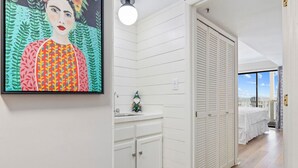 Un couloir aux murs blancs, un lavabo, un gnome vert et un lit avec vue.