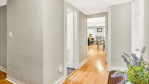 A hallway with grey walls and wooden flooring leading to a dining area with a table and chairs. - SUNNY PRIVATE 1 BEDROOM APARTMENT (Portland)