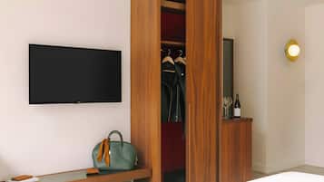 A modern room with a wooden wardrobe, a flat-screen TV, a desk with a handbag, and a wine bottle.