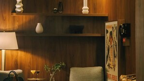 A modern room with wooden paneling, a sofa, a chair, a small table, and a lamp. - Hotel Henri NY (New York)
