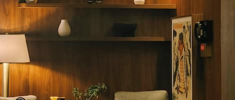 Et moderne værelse med træpaneler, en sofa, en stol, et lille bord og en lampe.