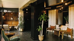 A modern interior with seating areas, potted plants, and a wooden reception desk. - Hotel Henri NY (New York)