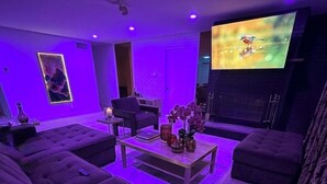 A modern living room with a large flat-screen TV, a sofa, a coffee table, and a fireplace.