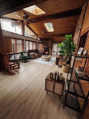 A spacious living room with a fireplace, wooden floors, and large windows. - Hines Villa in Wisconsin Dells (Wisconsin Dells)