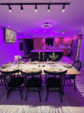 A dining area with a table set for six, a kitchen in the background, and purple ambient lighting. - Hines Villa in Wisconsin Dells (Wisconsin Dells)