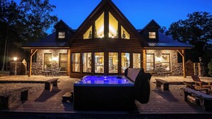 A log cabin with a hot tub, stone walls, and large windows. - The Retreat sleeps 32 (Fort Payne)