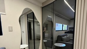 A modern living room with a sofa, a small round table, and a large mirror. - Aurea 210 (João Pessoa)