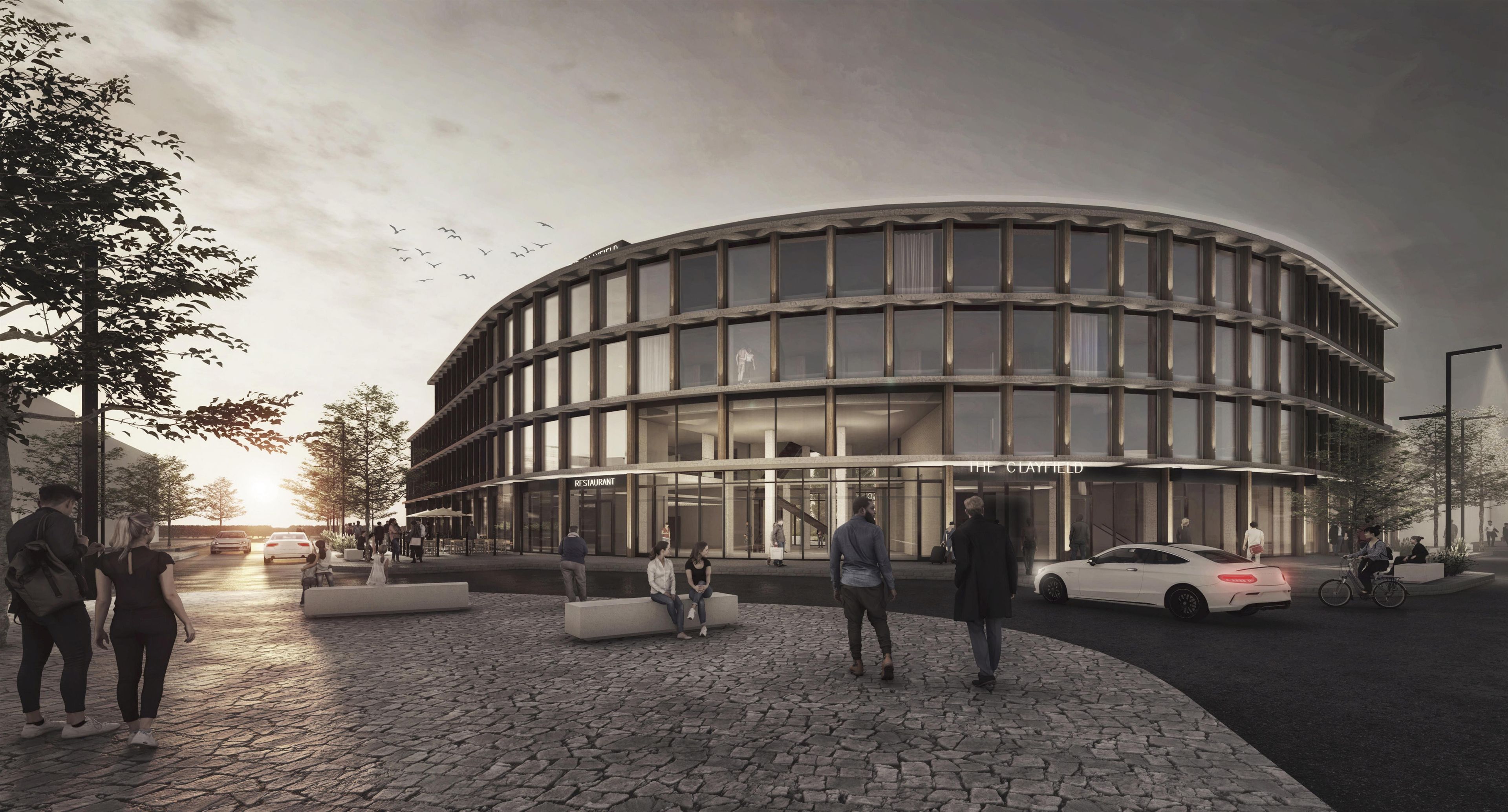 Un bâtiment moderne à la façade incurvée, avec une enseigne de restaurant, et une zone pavée où se trouvent des personnes et des voitures.