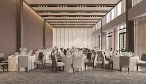 A spacious banquet hall with multiple round tables, each set with chairs and table settings.