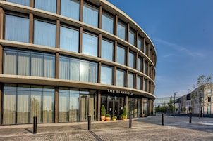 Un edificio moderno con fachada curva, ventanas amplias y un letrero que dice 'THE CLAYFIELD'.