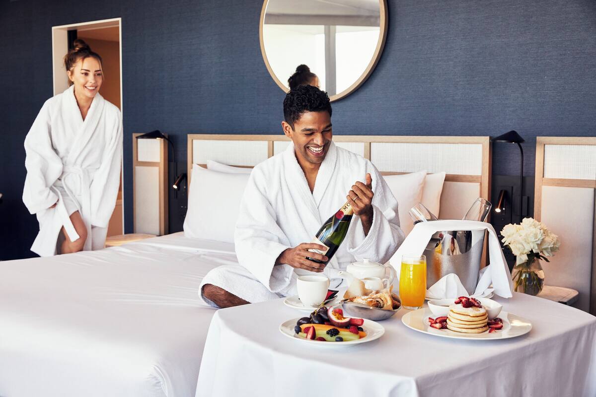 A hotel room with a bed, breakfast setup, and a mirror on the wall.