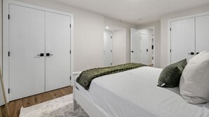 A bedroom with a bed, white wardrobe, and a mirror.