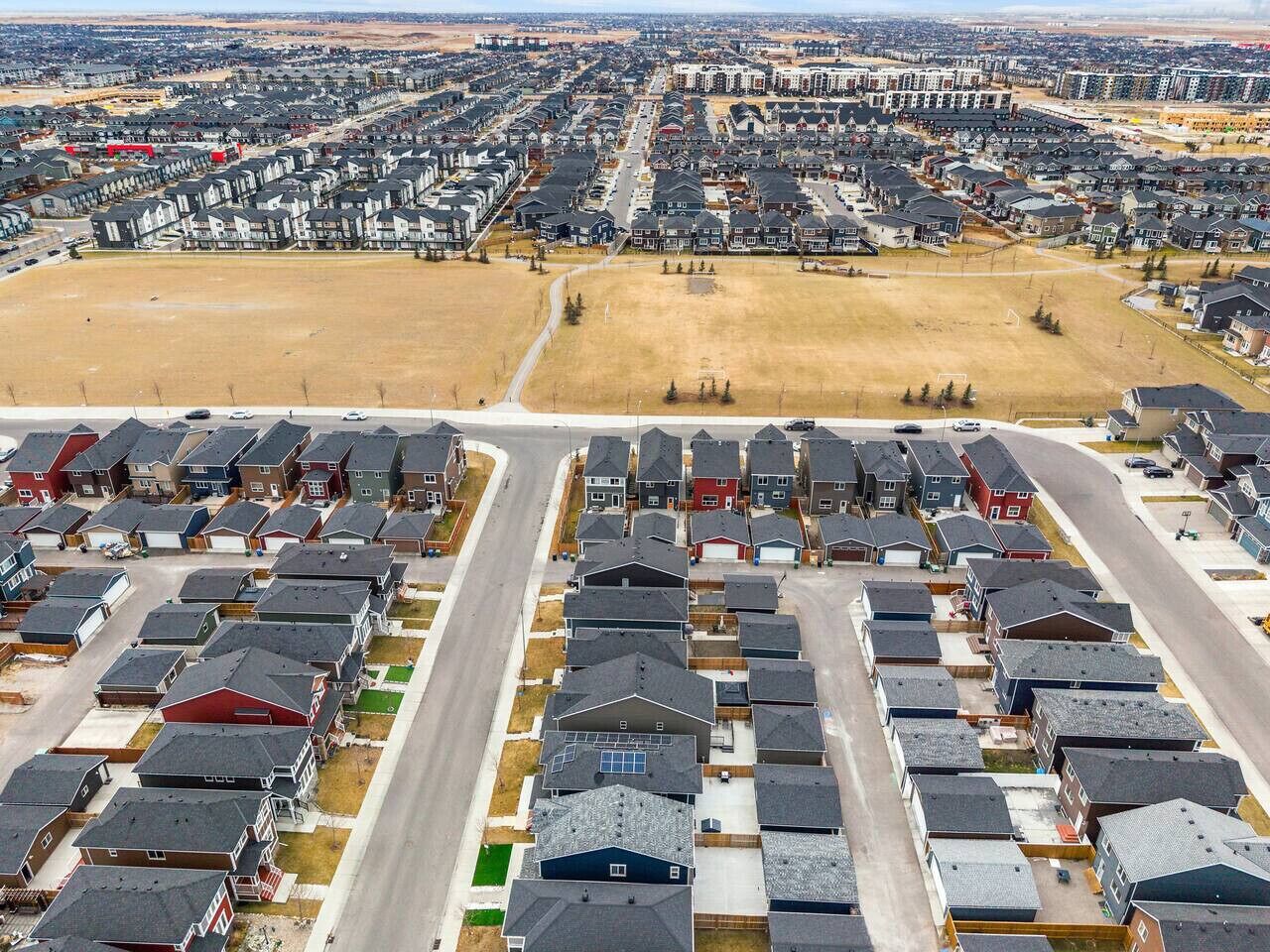 Een woonwijk met meerdere rijen huizen, een hoofdstraat en open ruimtes.