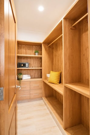 Ein Holzschrank mit offenen Regalen, einer kleinen Pflanze und einem gelben Kissen.