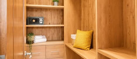 A wooden closet with shelves, a small plant, and a yellow cushion.