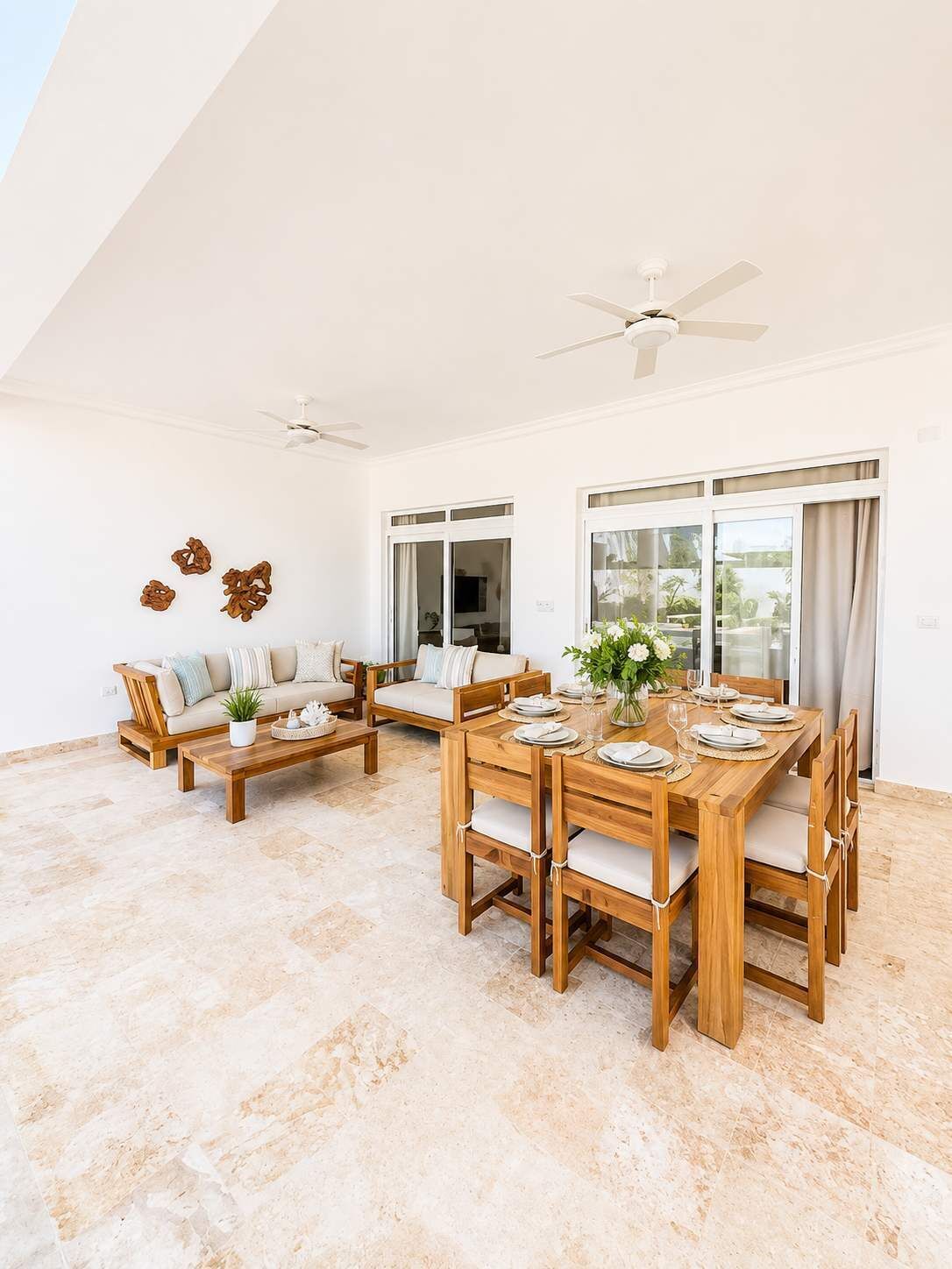 A spacious room with a wooden dining table set for four, a sofa, and a ceiling fan.