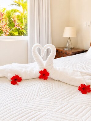 Quarto de hotel com cama, mesa de cabeceira com abajur e vista para o verde lá fora.