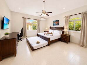 A hotel room with a bed, desk, chair, ceiling fan, and windows with curtains. - Sleeps up to 14 | 4 King Suites & Private Pool (Sosúa)