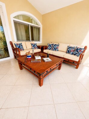 A living room with a wooden coffee table, two sofas with patterned cushions, and a large arched window. - Sleeps up to 14 | 4 King Suites & Private Pool (Sosúa)