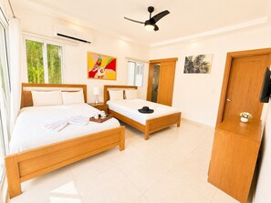 Een slaapkamer met een groot bed, een kleiner bed, een bureau en een kledingkast.