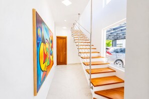 A modern interior with a staircase, a colorful abstract painting, and a view of parked cars. - Sleeps up to 9 | Family Retreat, Pool & Jacuzzi (Sosúa)