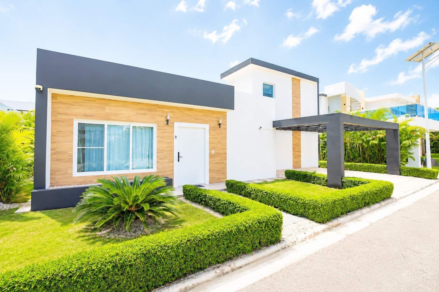 A modern two-story house with a well-maintained lawn and a covered outdoor seating area.