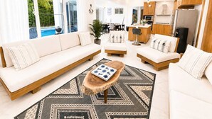 Ein modernes Wohnzimmer mit einer Sofagarnitur, einem Couchtisch und einem Essbereich mit Stühlen.