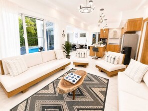 A modern living room with a sofa set, a coffee table, and a dining area with chairs. - Sleeps up to 9 | Family Retreat, Pool & Jacuzzi (Sosúa)