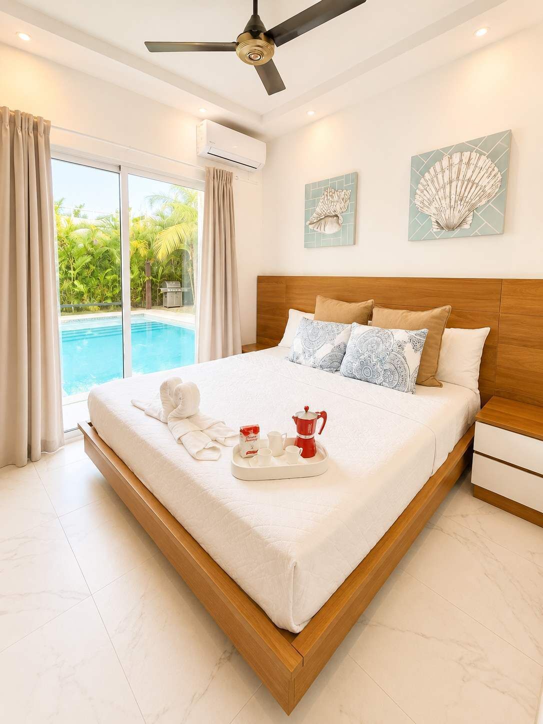 Une chambre spacieuse avec un grand lit, un ventilateur de plafond et une vue sur une piscine.