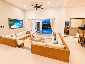 Ein modernes Wohnzimmer mit Blick auf einen Pool, einem Flachbildfernseher und einem Essbereich.