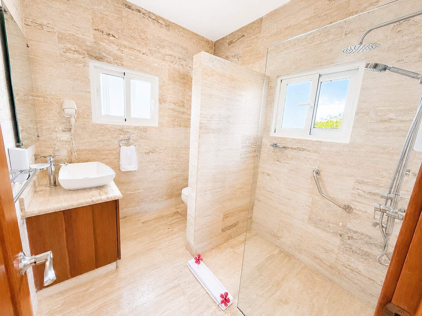 A bathroom with a shower, a sink, and a window.