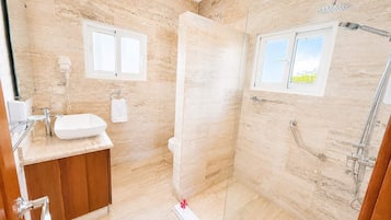 A bathroom with a shower, a sink, and a window.