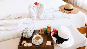 A hotel room with a bed, a bedside table with a lamp, a tray with breakfast items, and a hat on the chair. - Private Pool Villa | Large Yard & Sleeps up to 9 (Sosúa)