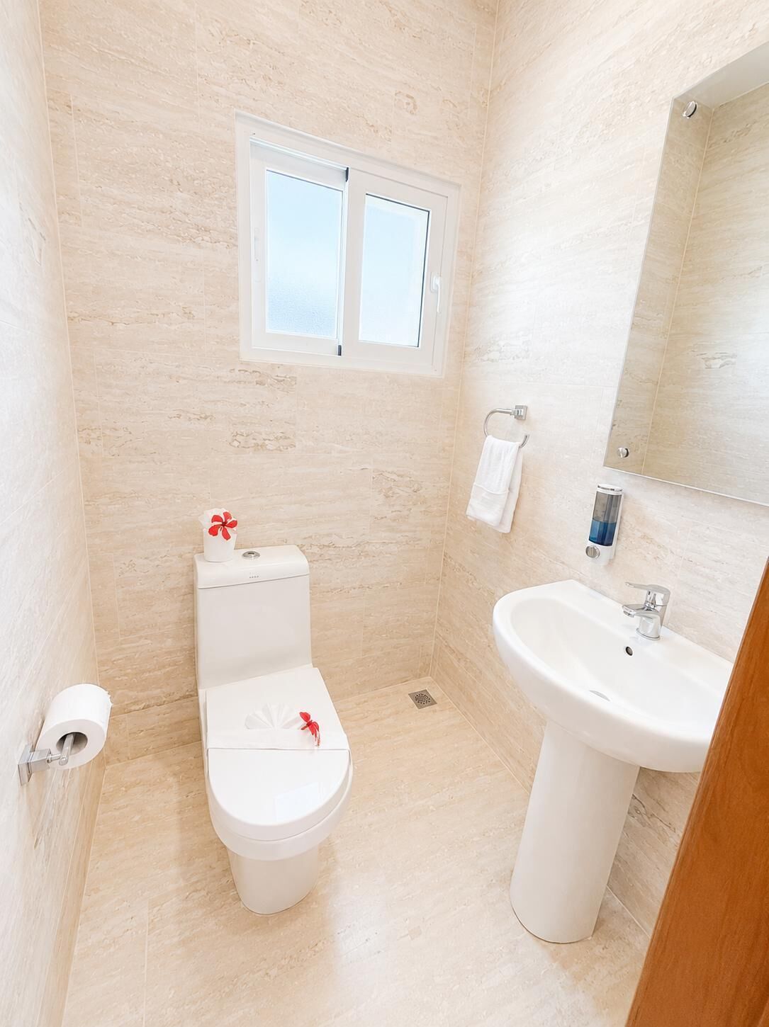 Een kleine, schone badkamer met toilet, wastafel en een raam.