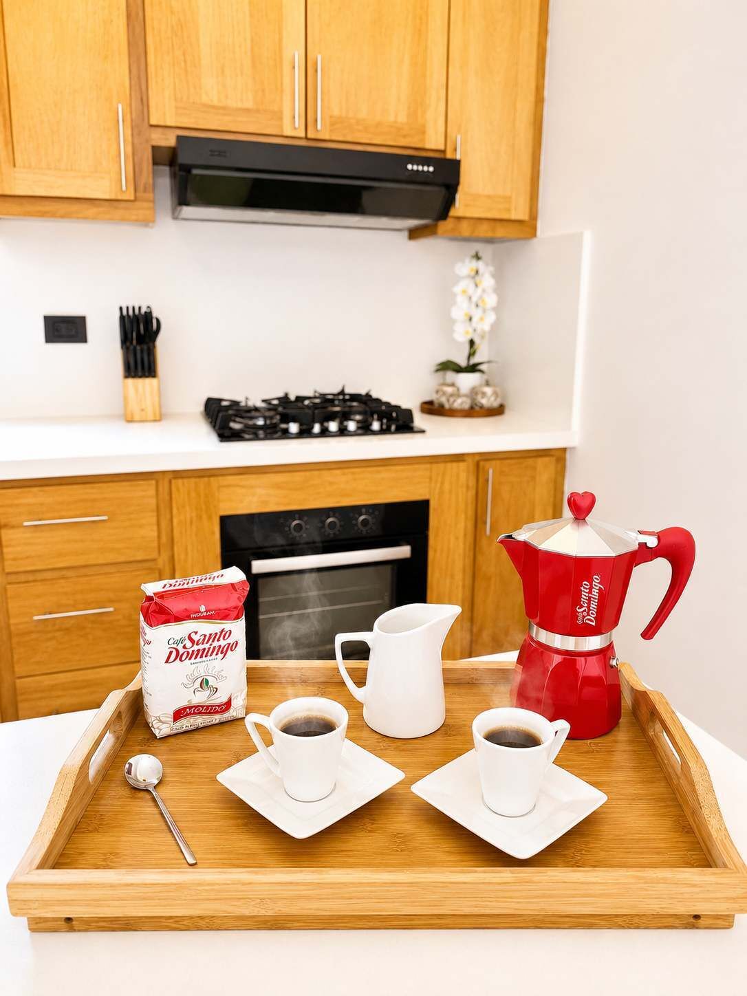 A kitchen with wooden cabinets, a gas stove, an oven, and a coffee maker on a tray with cups and a milk carton.