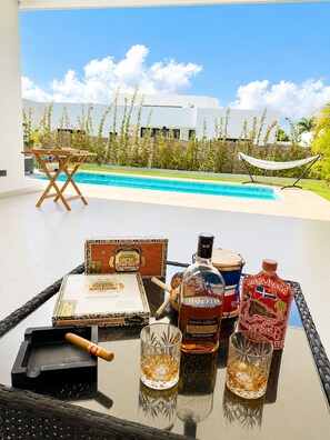 Ein Tisch am Pool mit einer Flasche Gran Anseo, einer Zigarre und zwei Gläsern.