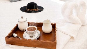 A neatly made bed with a tray of breakfast items, a black hat, and a white towel. - Modern Villa | Pool, Terrace & Sleeps up to 8 (Sosúa)