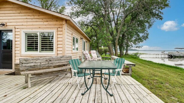 A wooden cabin with a deck, a table, and chairs. - Cozy Cabin on Big Pine Lake w/ Dock & Fire Pit! (New York Mills)