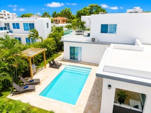 Ein moderner Poolbereich mit rechteckigem Pool, Liegestühlen und einer Pergola.