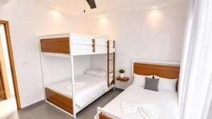 A hotel room with a bunk bed, a single bed, and a small bedside table with a plant. - Family Villa | Bunk Room, Pool & Up to 12 Guests (Sosúa)