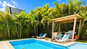 A clear blue pool with lounge chairs and a grill area, surrounded by lush greenery. - Family Villa | Bunk Room, Pool & Up to 12 Guests (Sosúa)