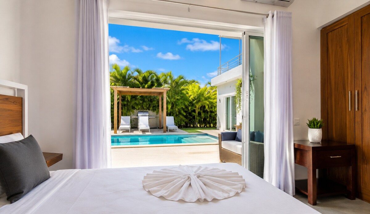 Ein Hotelzimmer mit Bett, Blick auf einen Pool und einem Holzschrank.