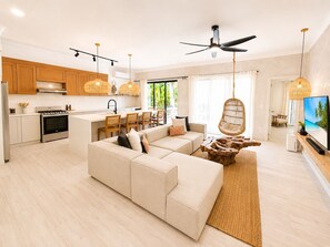 A modern living room with a sofa, a dining area, and a kitchen. - Boho Retreat |Pool Cabana, Terrace Lounge, Rooftop (Sosúa)